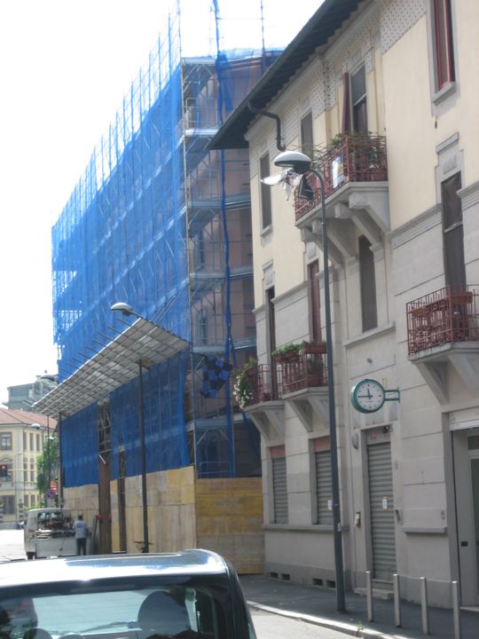 Palazzo d'epoca con ponteggio di facciata e rete di contenimento.