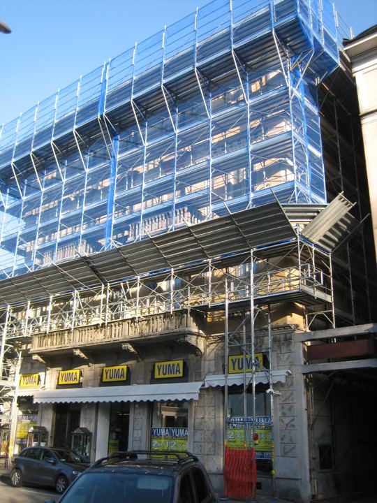 Ponteggio d'angolo sopra i negozi — continuità d'esercizio garantita.